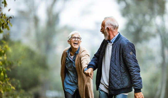 A senior couple laughing while on a walk.