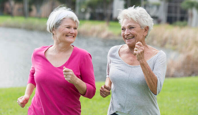 Two senior women walking and exercising outside